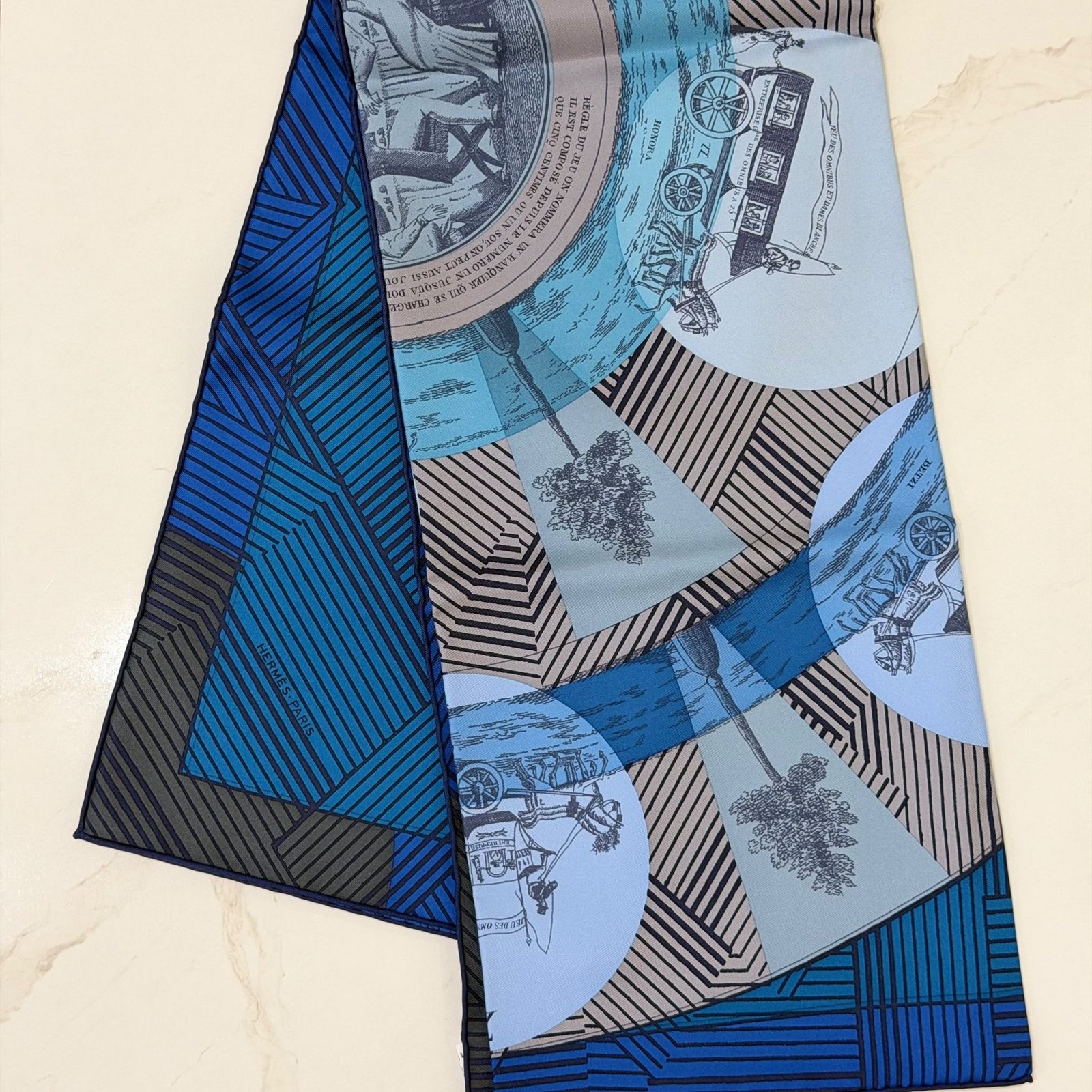 Hermès Jeu des Omnibus Remix silk scarf 90, folded with navy rolled hem