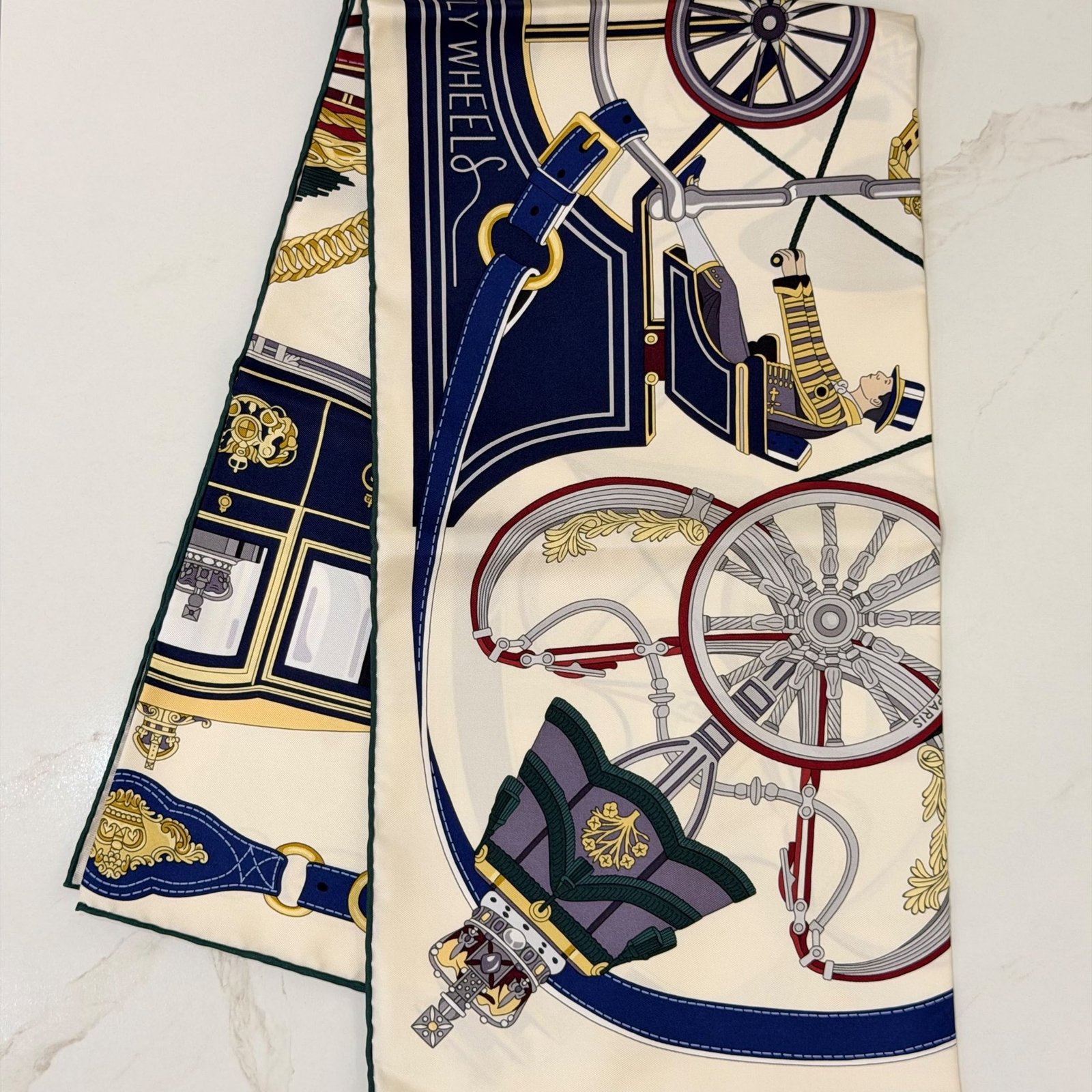 Hermès Stately Wheels silk scarf 90, folded to show the carriage wheel and coachman print